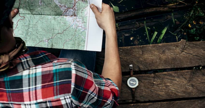 a group camping trip leader holds a map as they plan their next excursion