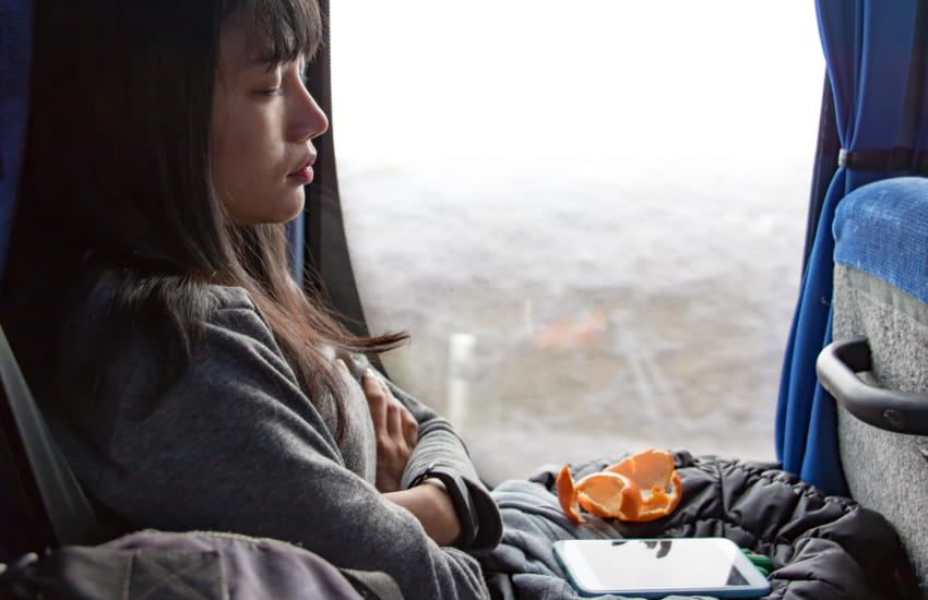 a charter bus passenger takes a nap while on the road