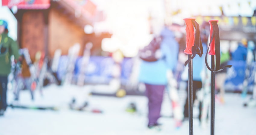 ski poles in the snow with skiers in the background