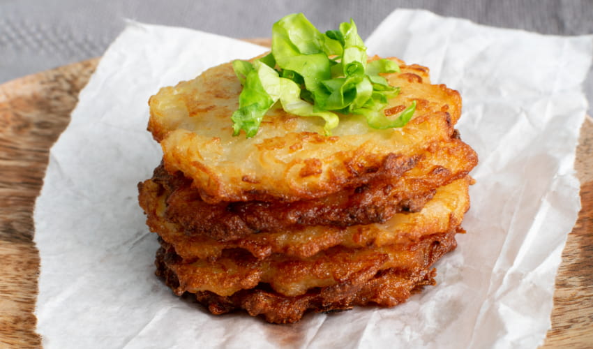 a tall stack of latkes garnished with shredded lettuce