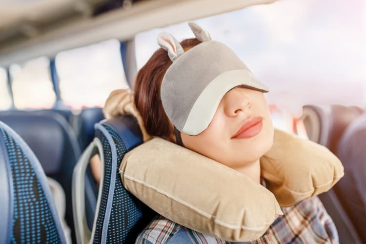 Woman with bunny eye mask sleeping on bus