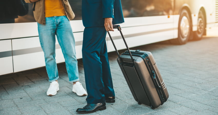 bus driver and passenger holding luggage outside charter bus