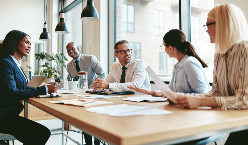 a group of employees engage in a meeting at a conference table