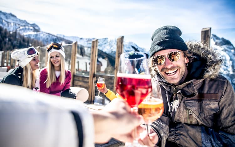 Skiers and snowboarders enjoying a ski trip with wine.