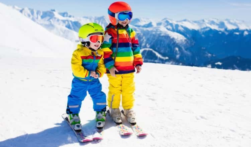 Two children in ski gear on top of a mountain