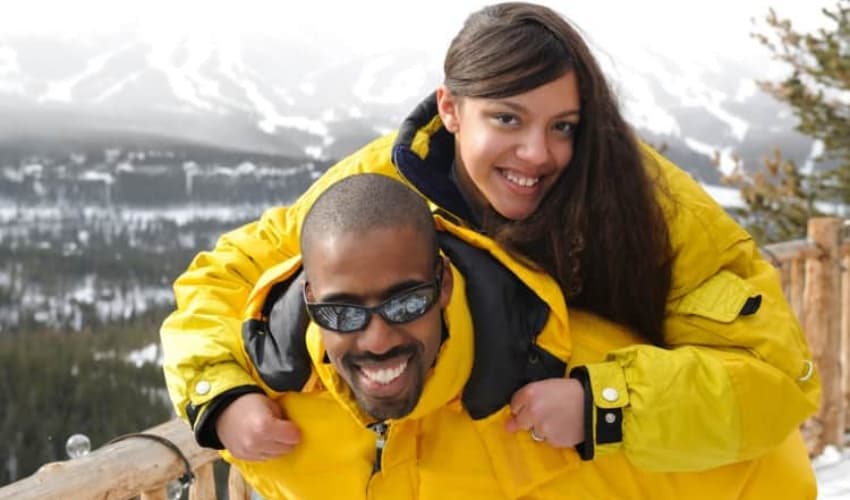 A man and woman on top of a mountain in ski gear