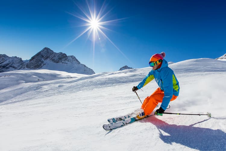 a man skis down a slope in Boston with the sun in the sky