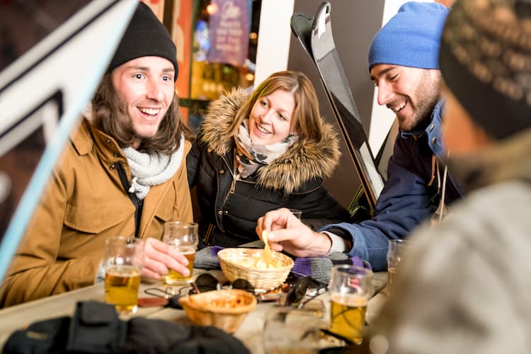 friends enjoy some drinks and snacks at a ski resort before heading back out to the slopes