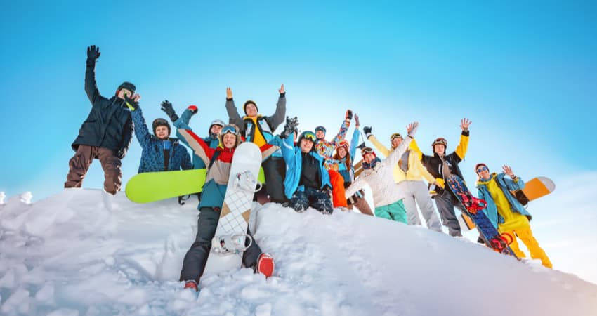 a big group of snowboarders taking a photo at the top of a mountain