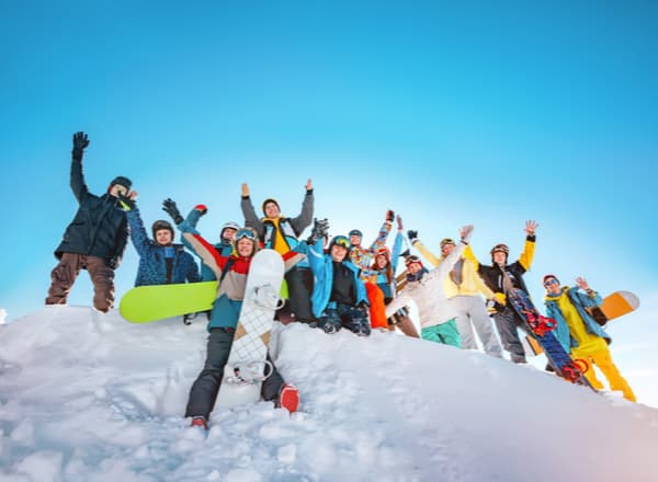 A group of snowboarders and skiers taking a photo on top of a mountain