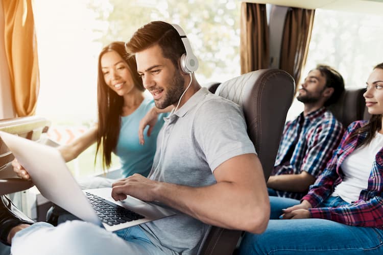 people on a bus trip working on a laptop while in transit