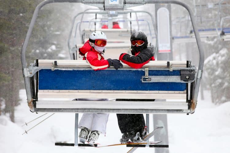 Two people on ski lift looking at camera