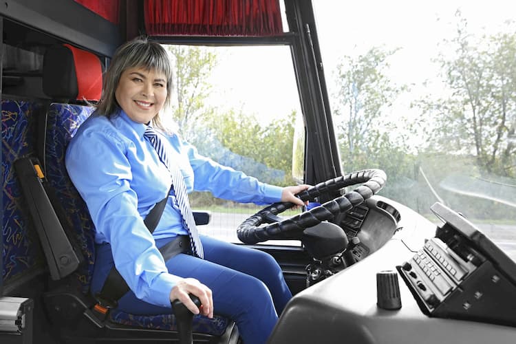 Woman driving bus and smiling