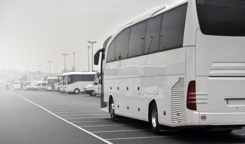 A charter bus parks in a foggy, bus-friendly parking lot