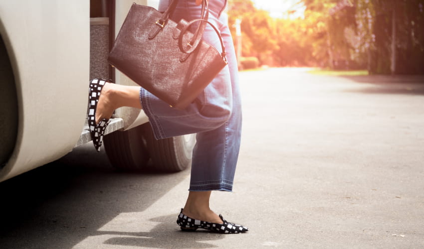 A woman with a bag steps off a charter bus