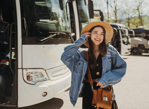 A woman walks by charter buses in a parking lot