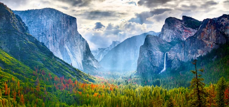 a view of yosemite valley with the sun's rays beaming through the clouds