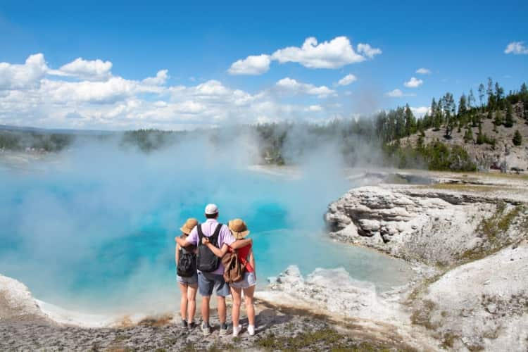 A group of three embracing eachother while staring at the horizon at Yellowstone National Park