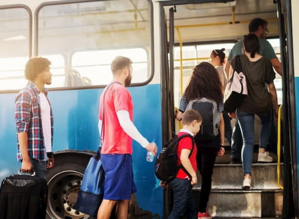 people wait in line to board a bus