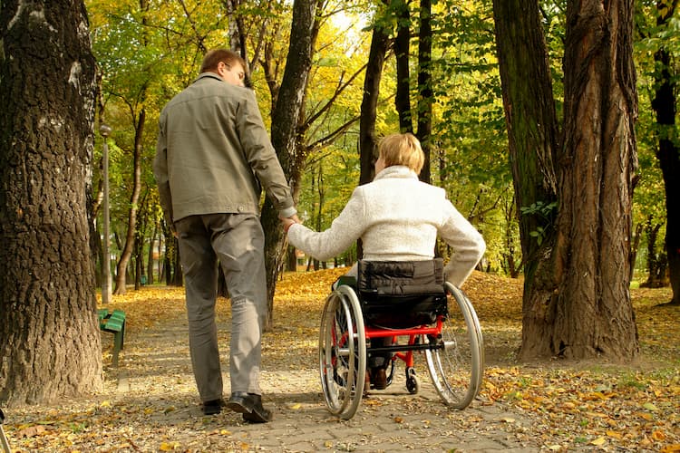 Couple in woods, one in wheelchair, one walking