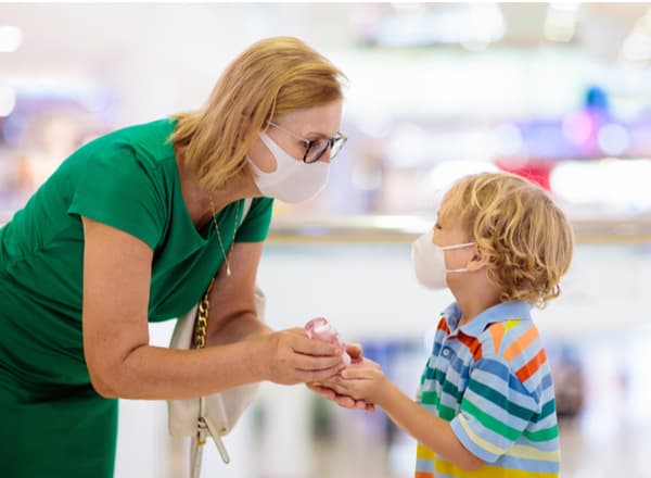 A woman and child wearing masks and using hand sanitizer