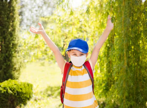 A child in the outdoors wearing a mask