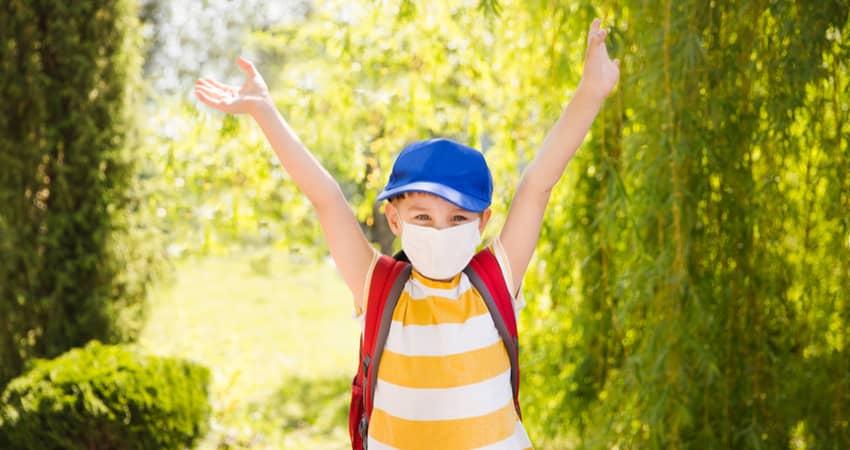 A child in the outdoors wearing a mask