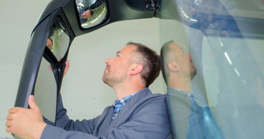 A charter bus driver inspects a bus mirror before a trip