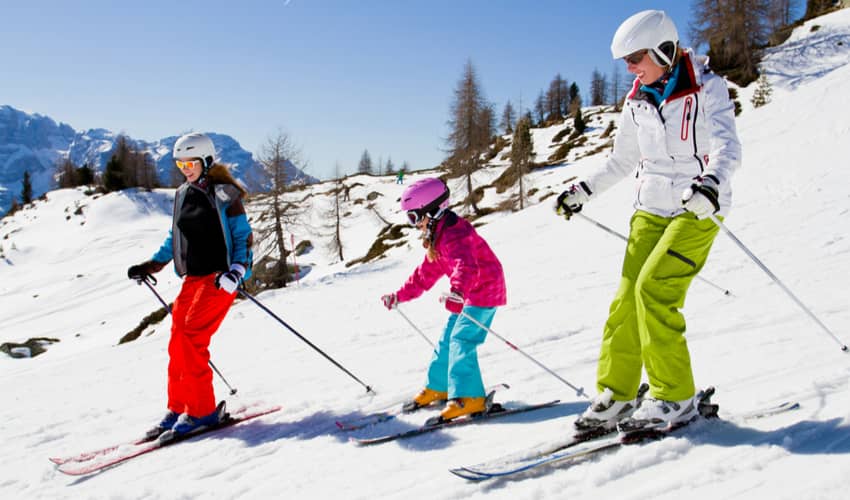 Two adults and a child skiing down a mountain