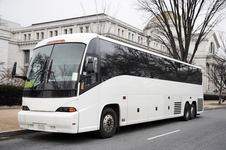 White charter bus parked in front of building