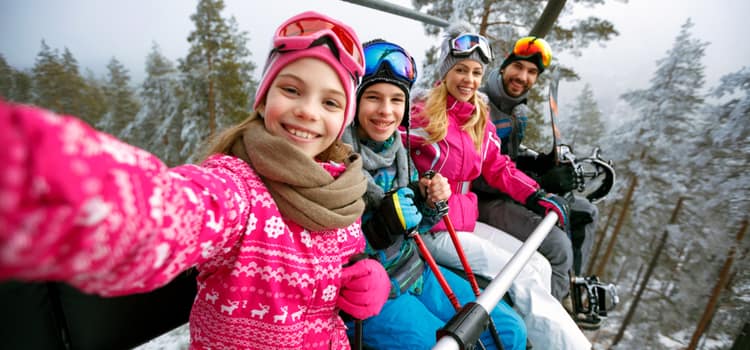 a family on a ski lift smiles for a selfie in the air