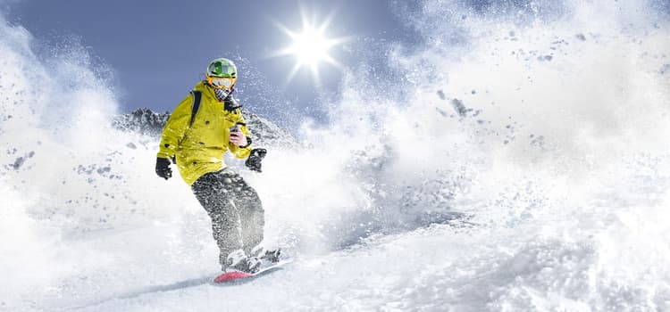 a skier slides down a snowy slope while snow puffs into the air around them