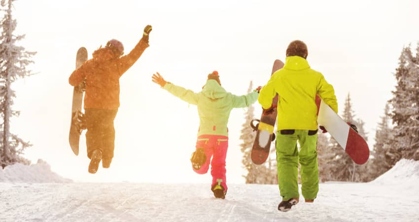 A group of people walking up a hill with snowboards