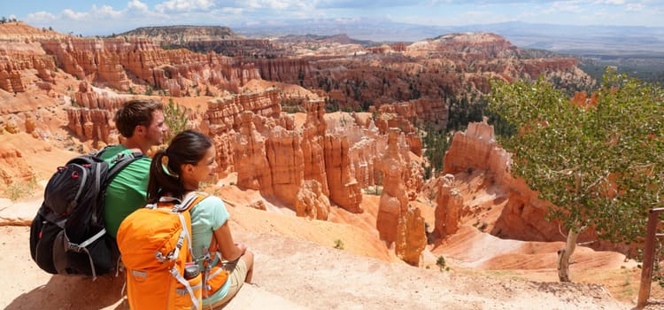 a couple sit atop a rock formation and look out into the canyon