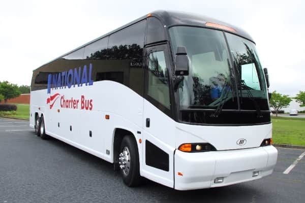 a plain white charter bus with large black windows and the "national charter bus" logo on the side