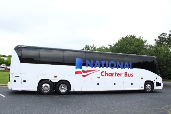 a plain white charter bus parked in a lot with the "national charter bus" logo on the isde