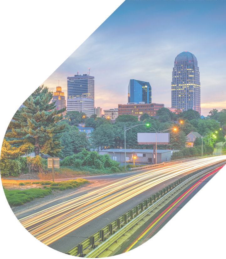 a long exposure of cars zooming down a busy highway at dusk with winston-salem in the background