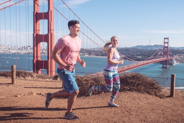 Two people running in a park near the Golden Gate Bridge