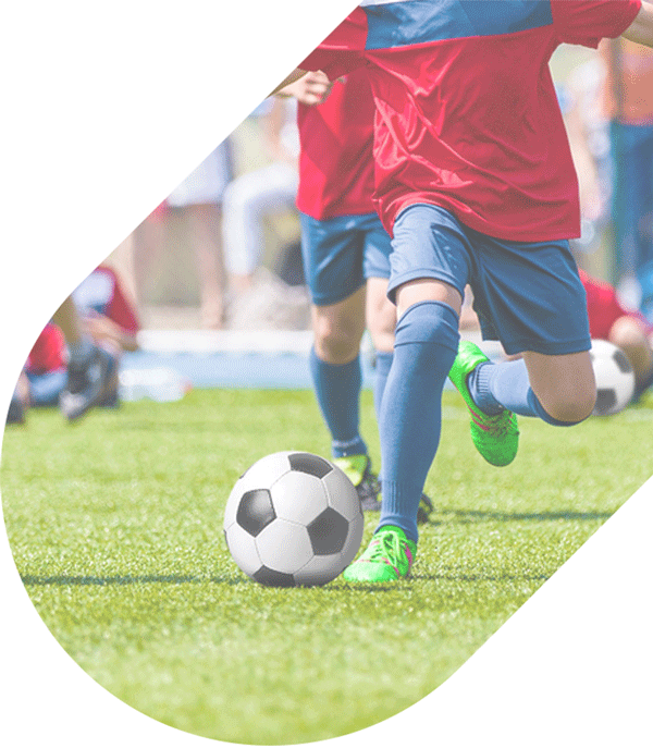 a young soccer player runs and kicks a soccer ball