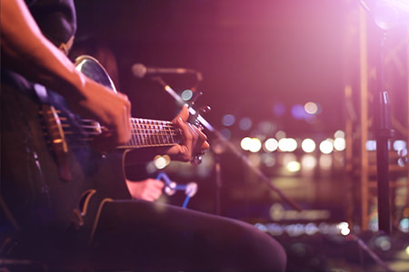 A musician plays guitar under stage lights