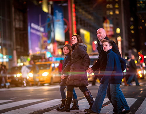 A family holds hands and crosses the street in a NYC borough