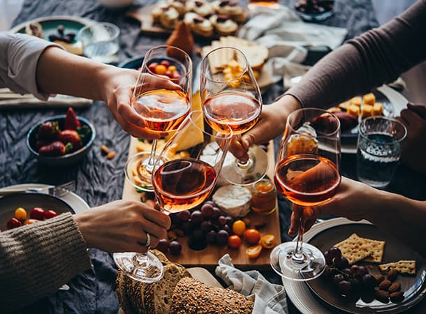 Guests toast glasses of wine at a dinner party