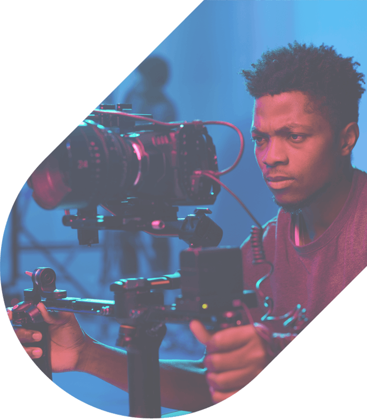 A filmmaker uses a camera on a stabilizer in a dim studio