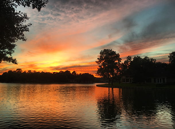 The sun sets over a pond in Sugar Land, TX