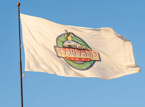 A white flag with a "pearland" logo on it flying against a blue sky