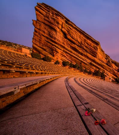 a row of seats at red rocks with a large layered rock in the background, at dusk