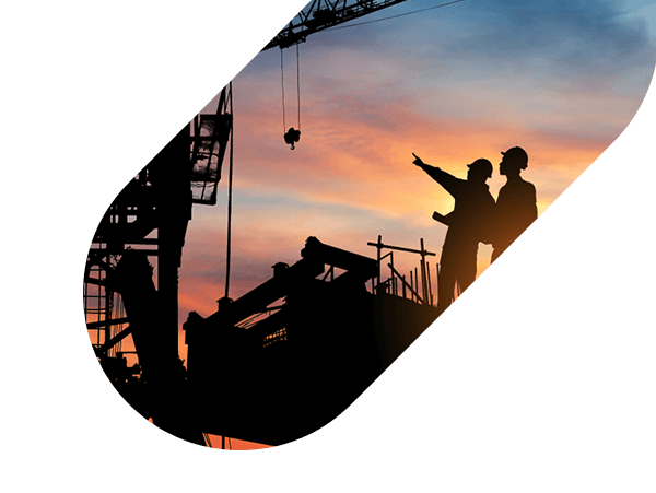 silhouettes of construction workers on site at sunset