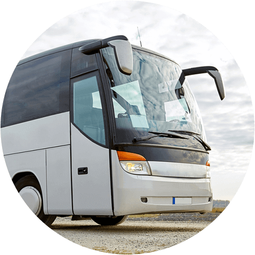 a gray charter bus parked against a cloudy sky