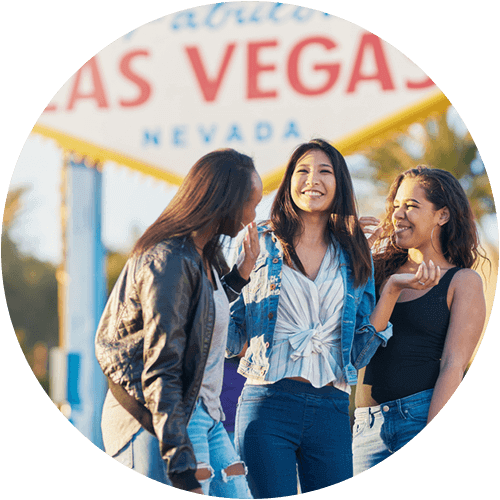 friends smile with the "welcome to fabulous las vegas" sign in the background