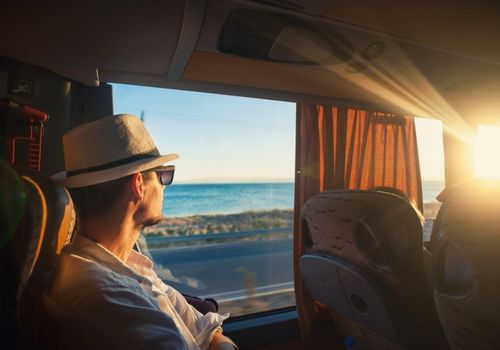 man looking out of the window of a charter bus